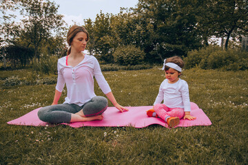 Woman doing yoga with her little girl. Healthy lifestyle.