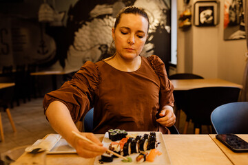 A woman eats lunch in a cafe, holds Chopsticks for sushi Chopsticks at lunchtime