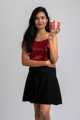 Portrait of a pretty young girl posing with gift box on grey background.