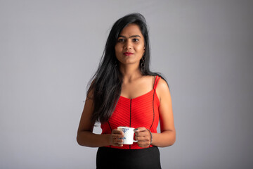 pretty young girl with a cup of tea or coffee posing on grey background