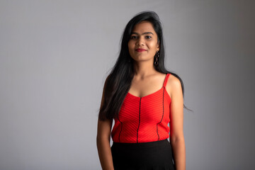 Young beautiful smiling girl in red and black outfit posing on grey background.