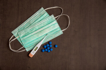 Medical mask with thermometer and tablets on a background virus epidemic coronavirus protection concept.