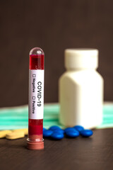 Tube containing a blood sample for testing to the presence of coronavirus / COVID-19 with Mask and medicine tablet.