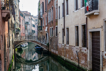 Fototapeta na wymiar Romanic view of a Water Canal (so-called Riva) in Venice, Italy. These waterways are the main means of transport in the city