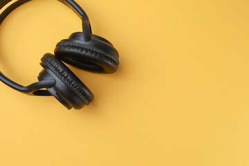 Black headphones isolated on the yellow background