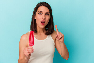 Young caucasian woman holding an ice cream isolated on blue background having an idea, inspiration concept.