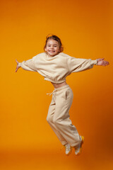 Fototapeta na wymiar Happy little girl jumping on a yellow background. Space for text.