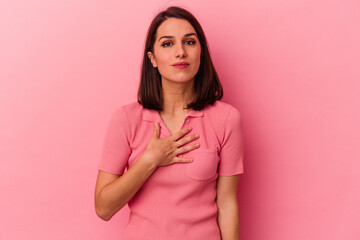 Fototapeta premium Young caucasian woman isolated on pink background taking an oath, putting hand on chest.