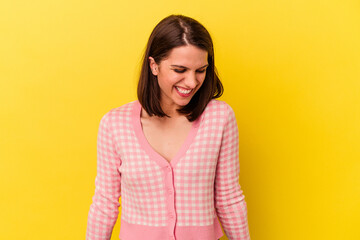 Young caucasian woman isolated on yellow background laughs and closes eyes, feels relaxed and happy.