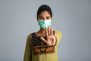 A portrait of woman with medical face mask showing stop sign with hands. Healthcare and medicine concept