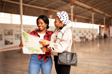 Beautiful girls looking for direction in the city. Young girlfriends travel together