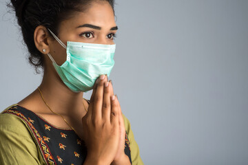 Portrait of a girl wearing a medical mask doing greeting with Namaste gesture.