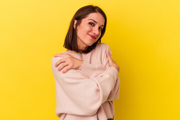 Young caucasian woman isolated on yellow background hugs, smiling carefree and happy.