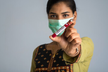 Woman holding a test tube with blood sample for coronavirus or 2019-nCoV analyzing.