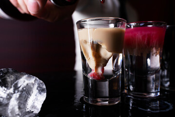 Barman preparing cocktail shots at the bar counter. Barman mixing drinks at the night club..