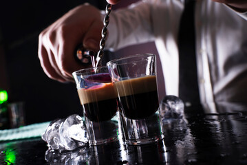 Barman preparing cocktail shots at the bar counter. Barman mixing drinks at the night club..