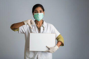 A young woman doctor in a medical mask holding a blank board, the concept of an epidemic of Coronavirus, Covid-19.