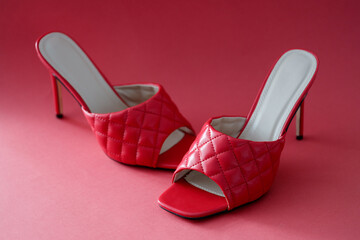 Women high heeled sandals standing on red background closeup