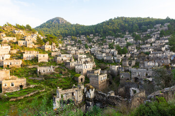 Fototapeta na wymiar Aerial view of abandoned ancient Greek village of Kayakoy overlooking remaining houses covering green mountainside, Turkey