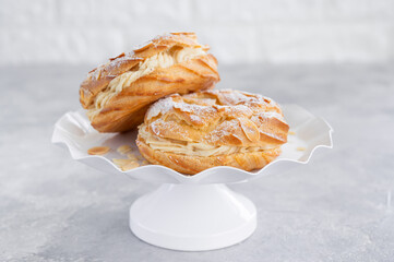 French traditional cake Paris Brest with praline cream, powdered sugar and almond petals on top on a gray concrete background. Copy space.