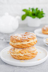 French traditional cake Paris Brest with praline cream, powdered sugar and almond petals on top on a gray concrete background. Copy space.