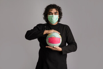 Young man holding world globe with a medicine face mask. World epidemic of coronavirus concept.