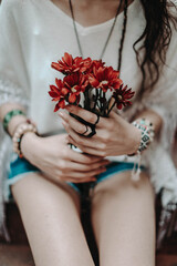 Female hands holding a bouquet of fresh red flowers. Hippie summer concept
