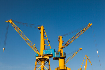 Yellow harbor cranes against the blue sky.