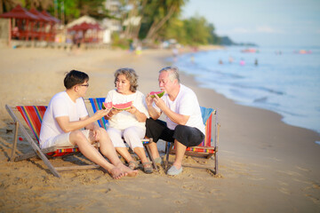 Happy Asian family enjoy talking together on the sunbed on the beach side restaurant.