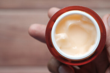 person hand holding a face cream container 
