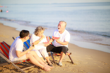 Fototapeta premium Happy Asian family enjoy talking together on the sunbed on the beach side restaurant.