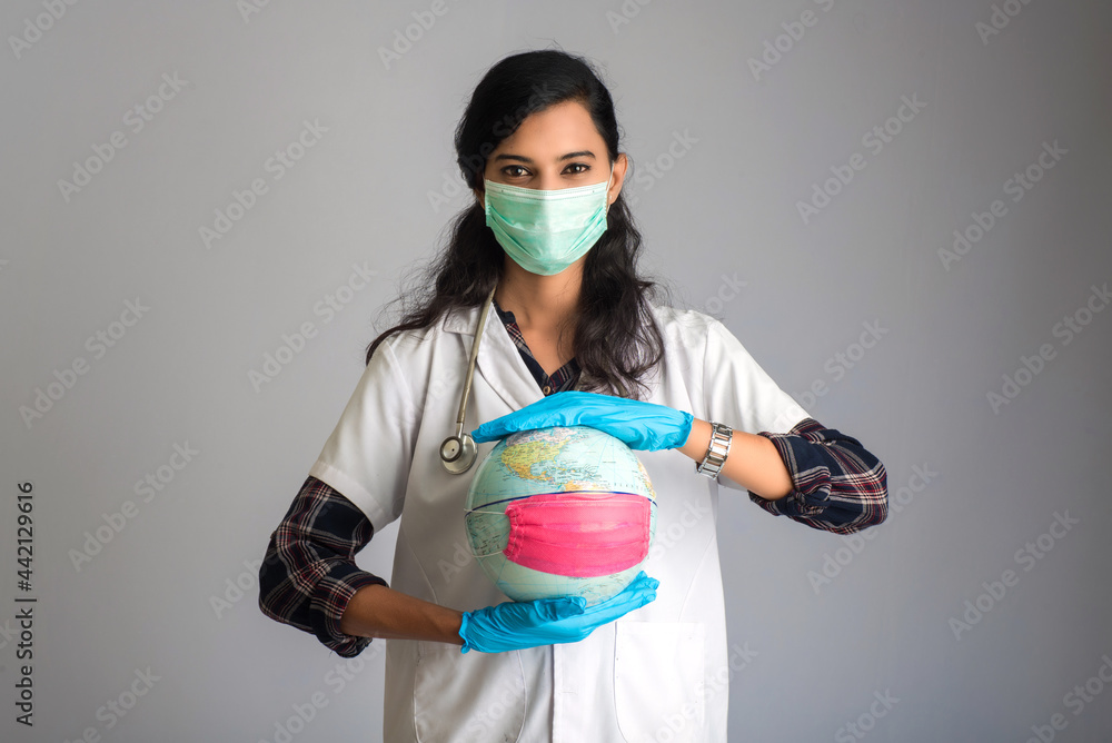 Wall mural woman doctor holding world globe with a medicine face mask. world epidemic of coronavirus concept.