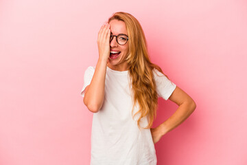 Caucasian blonde woman isolated on pink background having fun covering half of face with palm.