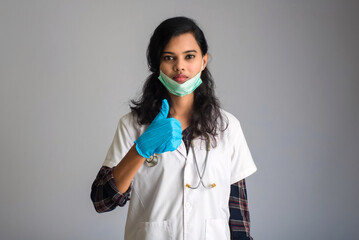 Young woman doctor wearing medical face mask Showing sign. Doctor woman wearing surgical mask for corona virus.