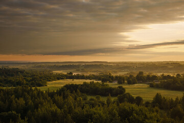 Forests and fields in the countryside and the sun shining through the clouds