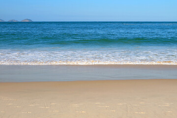 Gentle waves of the vivid blue sea splashing the empty beach