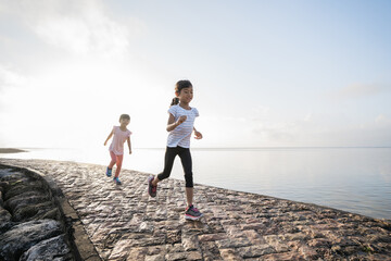 two Asian girl is jogging at the beach in the morning