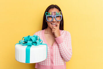 Obraz premium Young mixed race woman holding a cake isolated on yellow background biting fingernails, nervous and very anxious.