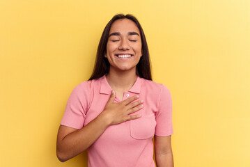 Obraz premium Young mixed race woman isolated on yellow background laughs out loudly keeping hand on chest.