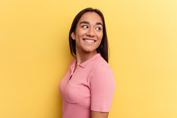 Young mixed race woman isolated on yellow background looks aside smiling, cheerful and pleasant.