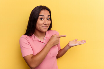 Young mixed race woman isolated on yellow background excited holding a copy space on palm.