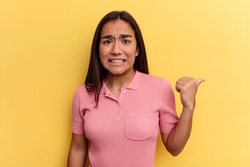 Young mixed race woman isolated on yellow background shocked pointing with index fingers to a copy space.