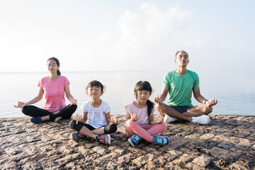 asian parent and children do sport outdoor. healthy family meditate together