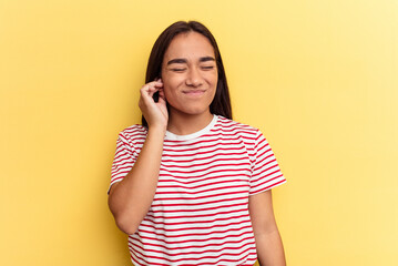 Young mixed race woman isolated on yellow background covering ears with fingers, stressed and desperate by a loudly ambient.