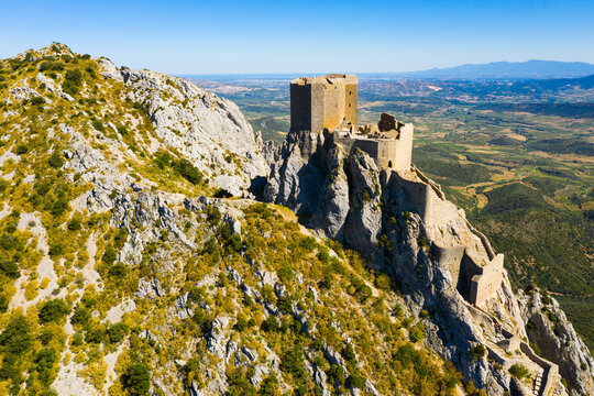 Aerial view of stone ruins of ancient fortified Chateau de Queribus on rocky hilltop on sunny summer day, Aude departement, France..
