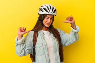 Young student caucasian woman wearing a bike helmet isolated on yellow background feels proud and self confident, example to follow.