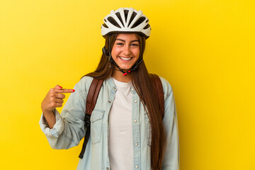 Young student caucasian woman wearing a bike helmet isolated on yellow background person pointing by hand to a shirt copy space, proud and confident