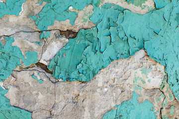 The texture of an old plastered wall with peeling blue paint. Natural background and pattern.