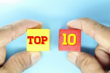 hand holding a wooden cube with the word Top 10