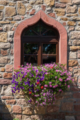 Fototapeta na wymiar Old window in an old stone house with decorative flowers in Kirchheimbolanden / Germany 